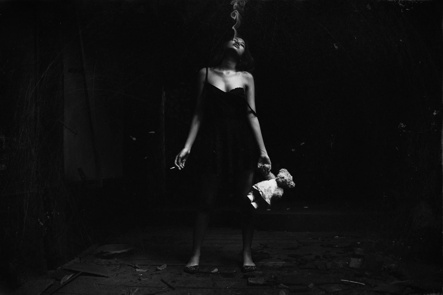 A woman in a black dress holding a doll in a dark room